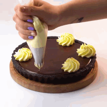a person with purple nails is frosting a chocolate cake