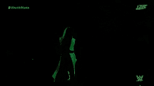 a person is walking in the dark with a green light behind them .