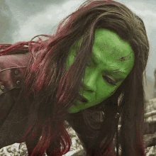a woman with red hair and a green mask on her face .