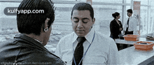 a man in a suit and tie is talking to a woman at an airport .