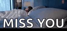 a woman is sleeping in a bed with the words miss you written above her