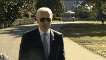 a man in a suit and tie wearing sunglasses is walking down a path