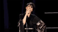 a woman in a black robe is standing on a stage and talking on a microphone .