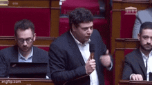 a man in a suit is speaking into a microphone in a parliament .