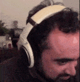 a man with a beard wearing headphones is sitting in a room .