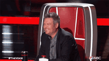 a man in a suit is sitting in a chair with a nbc logo on the bottom