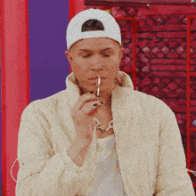 a man wearing a white hat and a white jacket is smoking