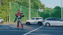 a man in a superhero costume is standing in a parking lot with cars parked behind him