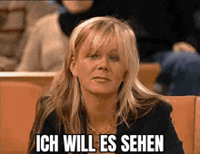 a woman is sitting in a classroom with the words ich will es sehen written on the screen .