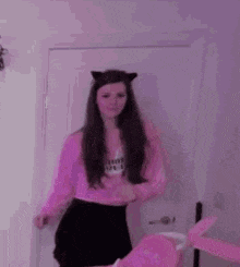 a woman wearing a pink sweater and black skirt is standing in front of a door .