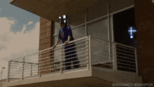 a man standing on a balcony with idiocracy written on the bottom right