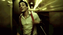 a man in a white shirt and red suspenders is dancing in a dark room