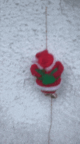 a stuffed santa claus is hanging from a chain on a white wall
