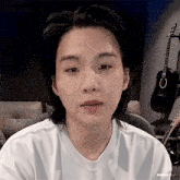 a close up of a person wearing a white shirt with a guitar in the background