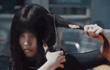 a woman is cutting her hair with scissors in a room .