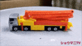 a yellow and red toy truck is sitting on a white table with chinese writing on the bottom .