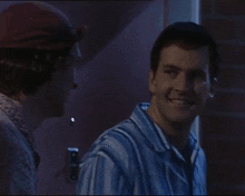 a man in a blue and white striped shirt talks to another man in a red hat