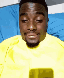 a man in a yellow shirt is laying on a blue bed