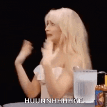 a naked woman is sitting at a table with a glass of water and a bottle of hot sauce .