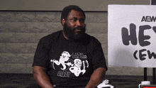 a man sitting in front of a sign that says he crew