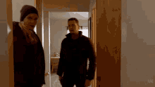 a man and a woman are standing in a hallway looking at each other .
