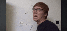 a man wearing glasses is standing in front of a laptop computer .