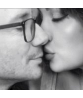 a man wearing glasses is kissing a woman on the cheek