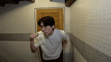 a man brushing his teeth in a bathroom wearing a white shirt that says essential
