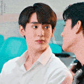 a man in a white shirt and tie looks at another man in a black shirt and tie