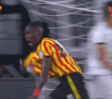a soccer player wearing a yellow and red striped shirt with the number 7 on it