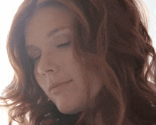 a close up of a woman with her eyes closed and her hair blowing in the wind