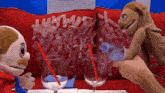 two stuffed animals are sitting on a red couch with a bottle of water