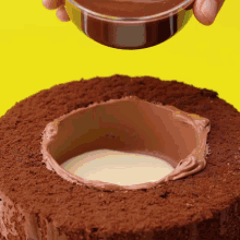 a chocolate cake is being decorated with a bowl of chocolate icing