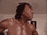 a shirtless wrestler is standing in front of a picture of a man
