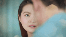 a close up of a woman 's face with a man 's face in the background