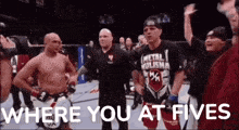 a man in a metal hulisha shirt stands in a boxing ring with other men