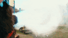 a person is standing in a field with smoke coming out of their mouth