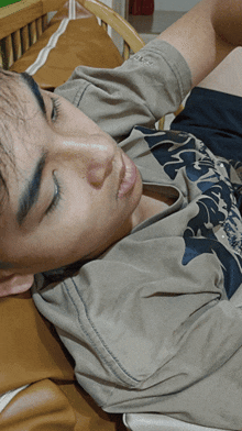 a young man laying on a bed with his eyes closed wearing a shirt that says ' shark ' on it