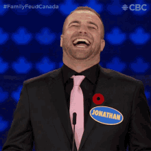 a man wearing a black suit and a pink tie has a name tag that says jonathan