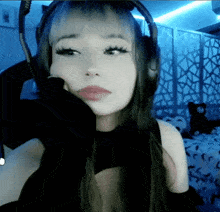 a woman wearing headphones and a black top looks at the camera