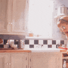 a woman wearing sunglasses and a red hat is standing in a kitchen