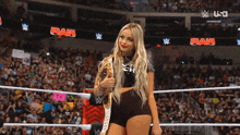a woman is standing in a wrestling ring holding a championship belt ..
