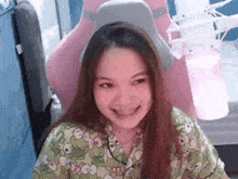 a woman is smiling while sitting in a pink gaming chair
