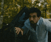 a man in a blue and white striped shirt is looking out of a car window