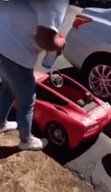 a man standing next to a red mustang car
