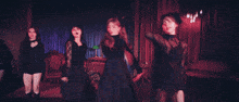 a woman in a black dress is dancing in front of a red curtain