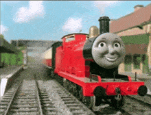 a red train with a smiling face is on a track