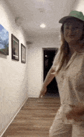 a woman is dancing in a hallway with paintings on the wall behind her