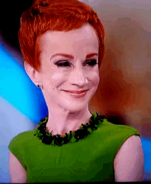 a woman with red hair is wearing a green top and black necklace