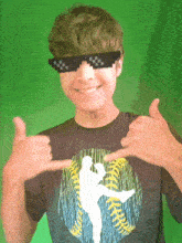 a boy wearing sunglasses and a baseball shirt is making a funny face